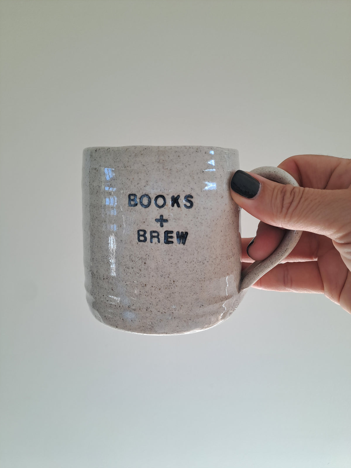 Books + Brew mug being held in Steph's hand.
