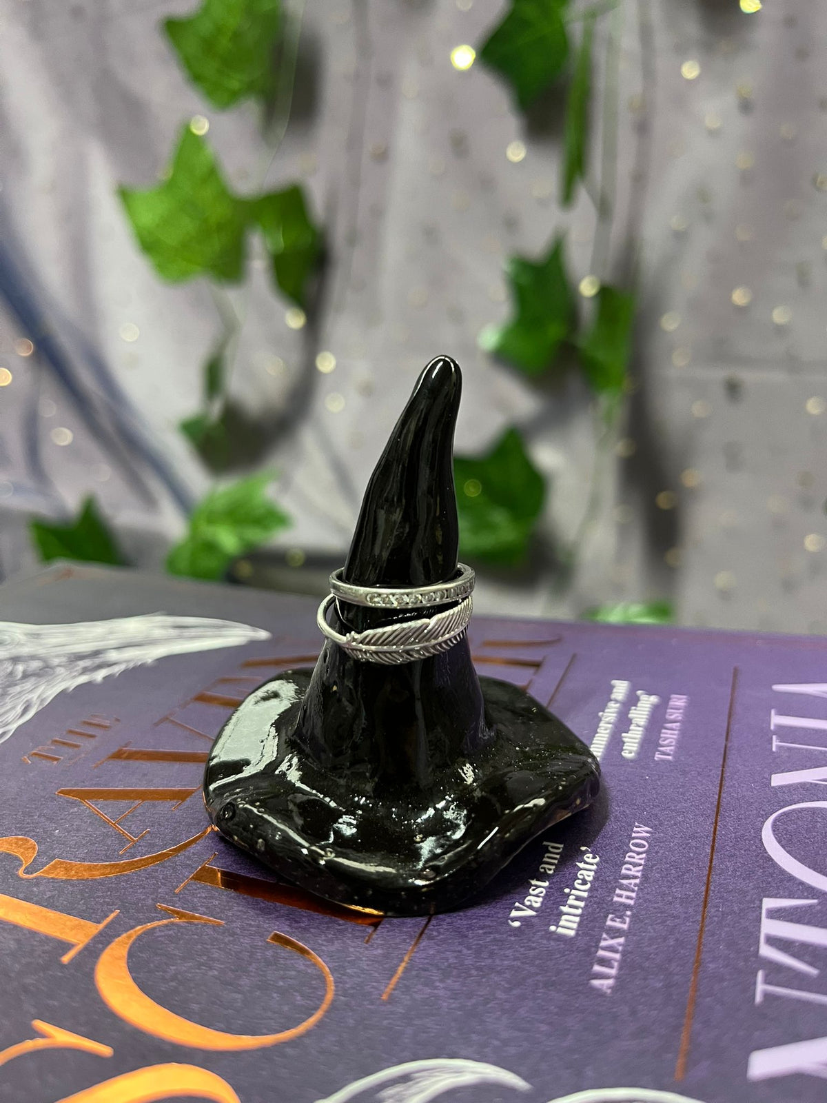 Black witch's hat with silver rings on a purple book with text