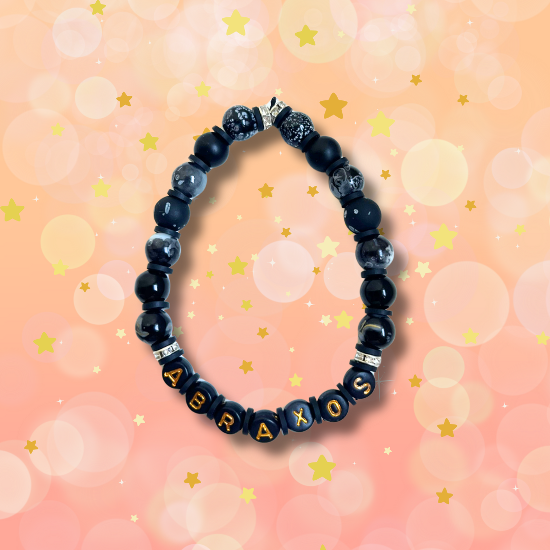 Black beaded bracelet with the word Abraxos, on a peach coloured background with stars.
